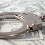 A closeup shot of metal handcuffs and dollars